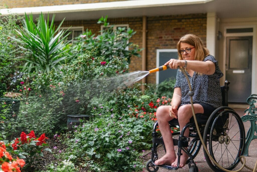 Woman on wheelchair watering plants